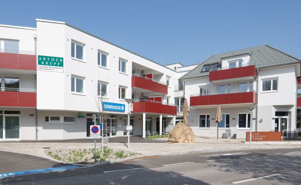 Moderne Gebäude mit Geschäftsschildern und Balkonen an einem sonnigen Tag.